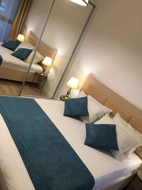 a bedroom with two beds with blue pillows and a mirror at Adams Apartment Onix Blue in Mamaia Sat/Năvodari