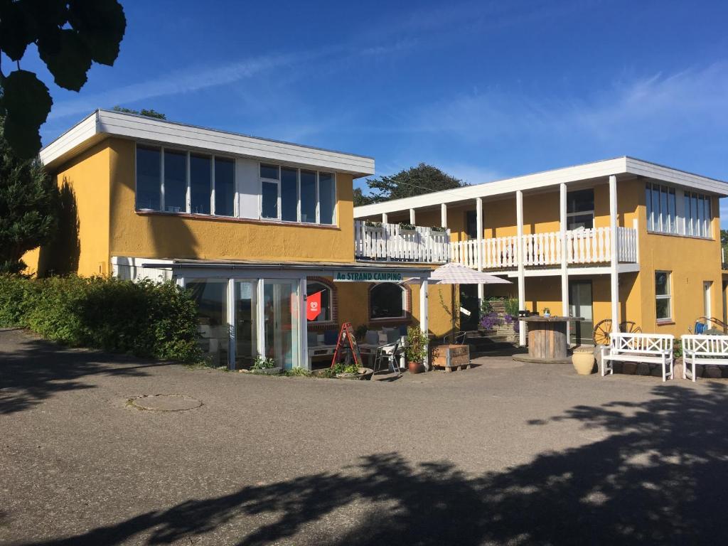 a yellow and white building with a white balcony at Aa Strand Camping in Ebberup