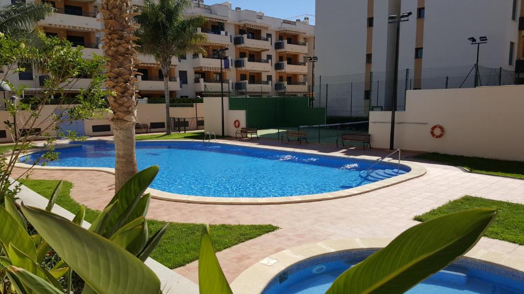 Apartamento en playa de Almenara con vistas a la Marjal في المنارة: مسبح بالنخيل ومبنى