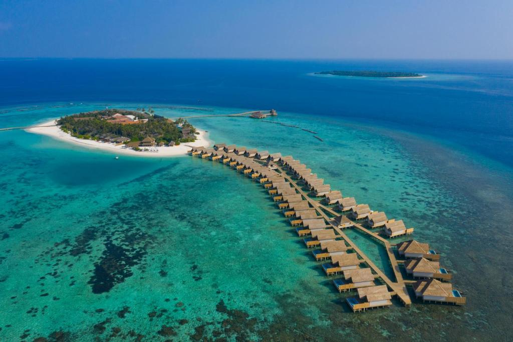 an island with a wooden bridge in the water at Emerald Faarufushi Resort & Spa - Deluxe All Inclusive in Raa Atoll
