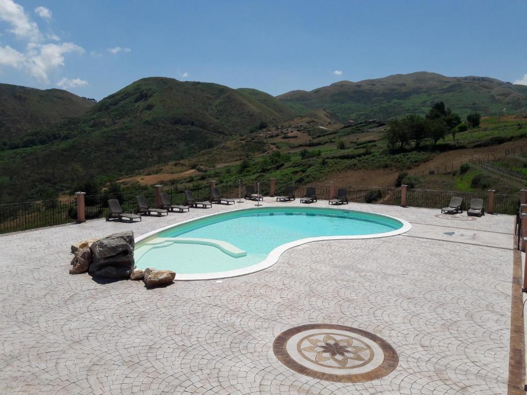 una piscina con sedie e montagne sullo sfondo di Monte San Giovanni-Nebrodi Rooms a San Marco dʼAlunzio