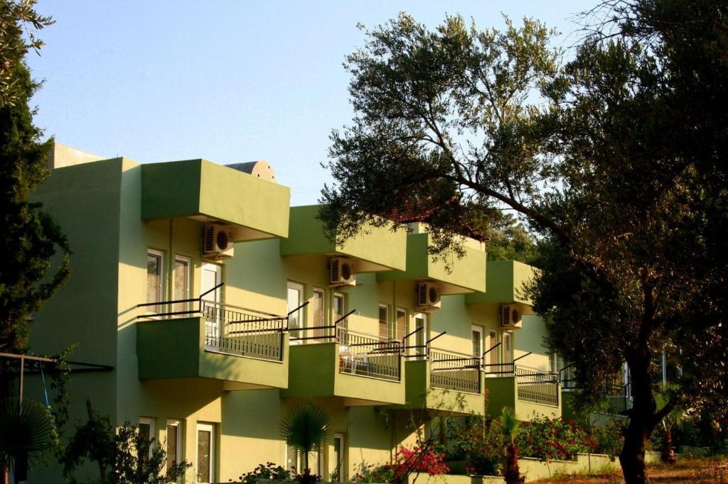 a green building with balconies on the side of it at Patara Caretta Hotel in Patara