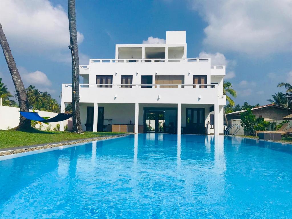 a white house with a swimming pool in front of it at Silverlane Beach House in Matara