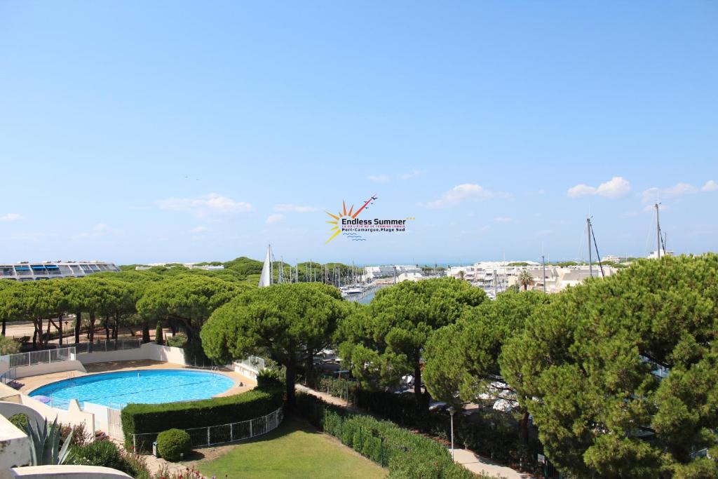 a resort with a swimming pool and trees at Studio 237 Port Camargue, Piscine, Climatisation, 2 personnes in Le Grau-du-Roi