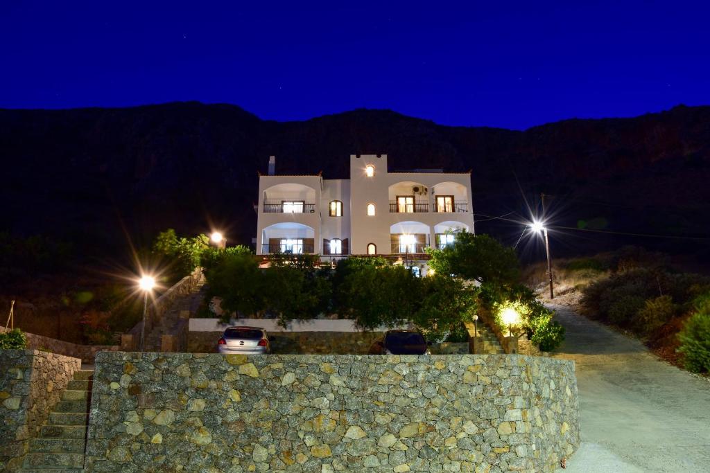 a large white house with a stone wall at night at Paraschou Guesthouse in Monemvasia