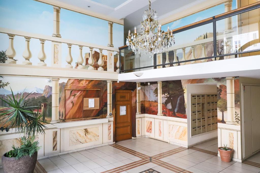 een grote kamer met een kroonluchter en schilderijen aan de muren bij CANNES Palazzio in Cannes