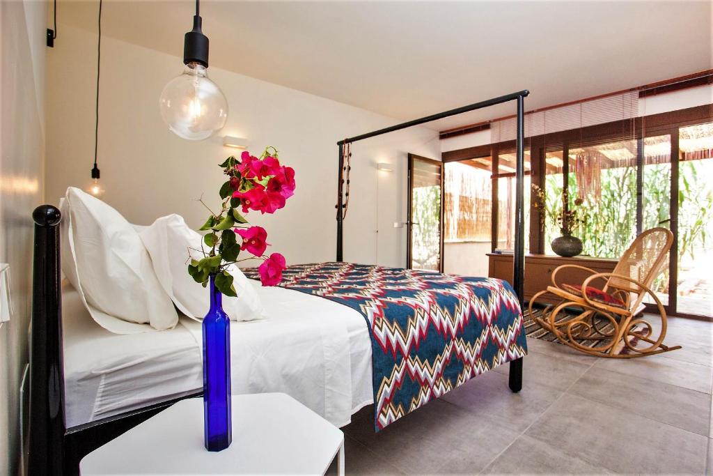1 dormitorio con 1 cama y un jarrón con flores sobre una mesa en Idayvuelta Home & Suites, en Ses Salines