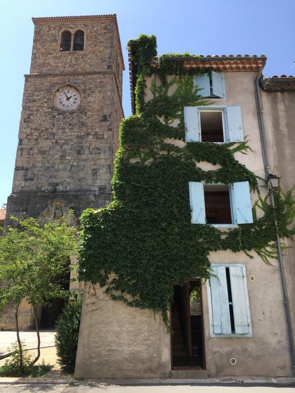 un edificio con una torre de reloj con hiedra. en Entre l'église et la place, en Quillan