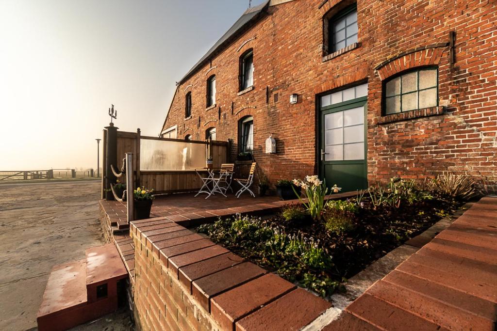 ein Backsteingebäude mit einer grünen Tür und einer Terrasse in der Unterkunft Ferienwohnung Hooge Hörn in Borkum