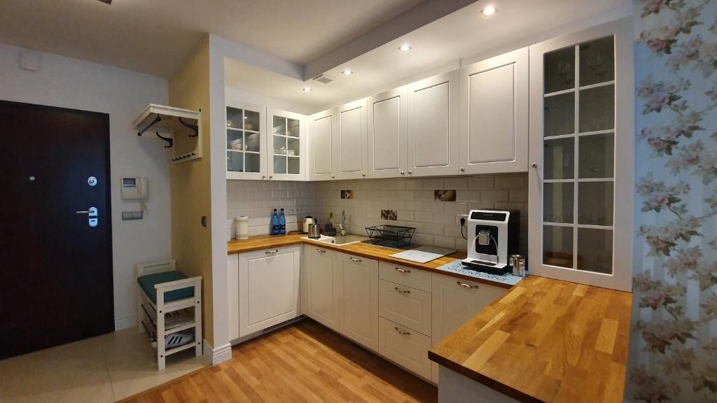 a large kitchen with white cabinets and a microwave at Apartament Jurata in Jurata