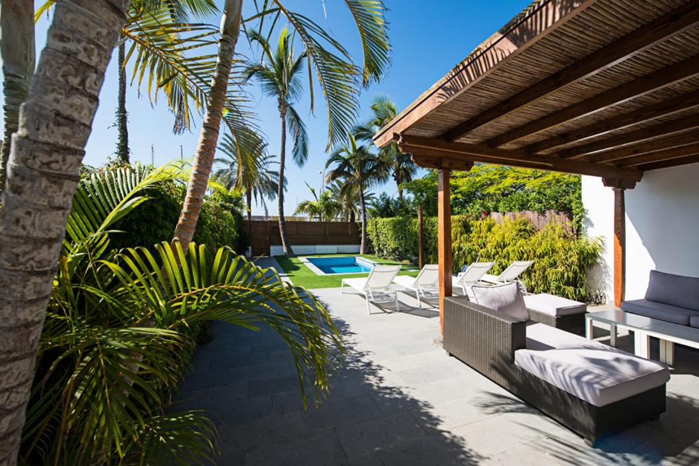 un patio con tumbonas, pérgola y piscina en Villas Pasito Blanco, en Pasito Blanco