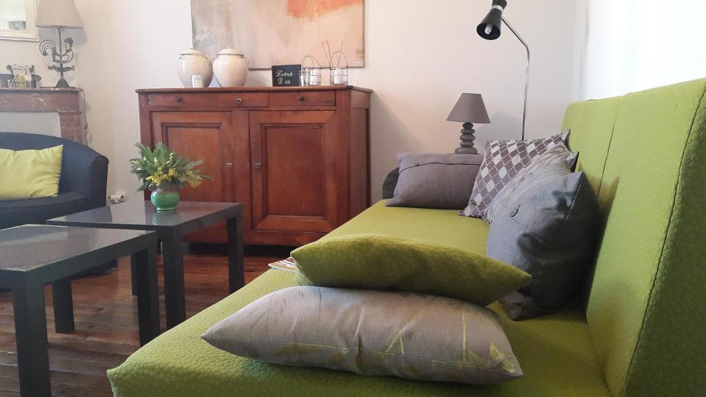 a living room with a green couch with pillows on it at Le gîte de l'atelier in Bergerac