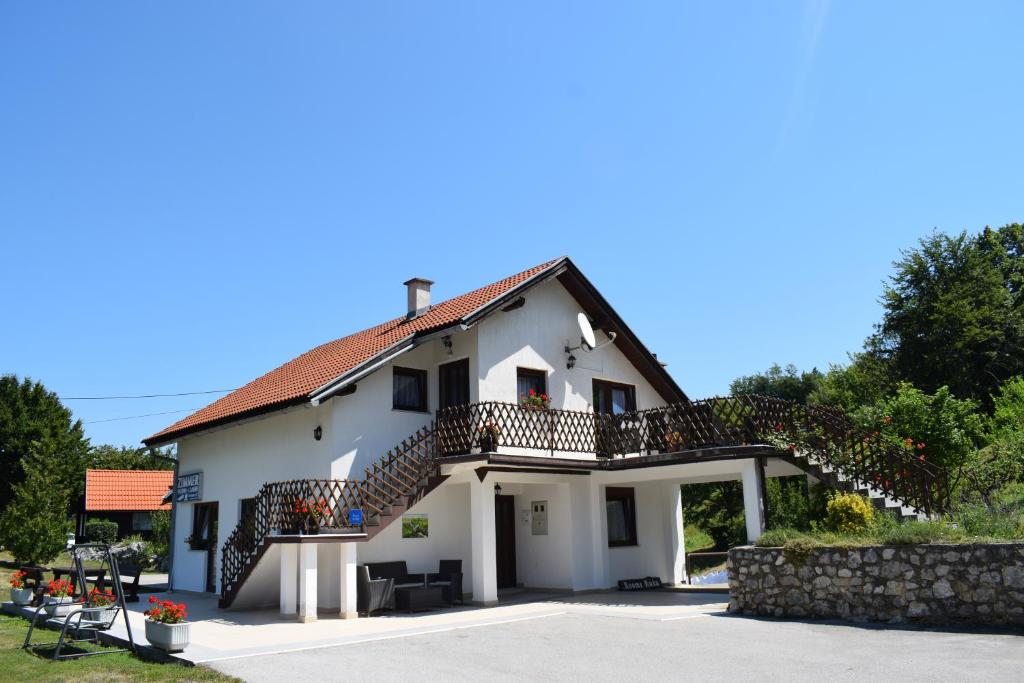 una casa blanca con una escalera delante en Rooms Ruza, en Smoljanac