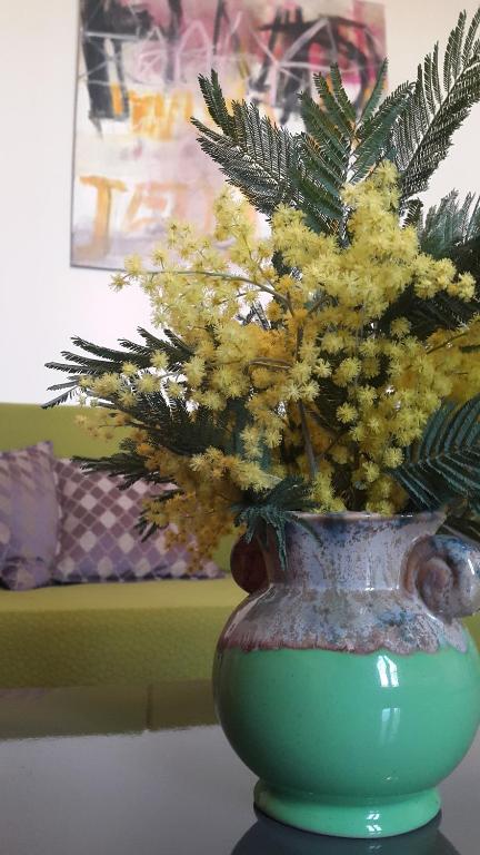 a green vase with yellow flowers in it at Le gîte de l&#39;atelier in Bergerac