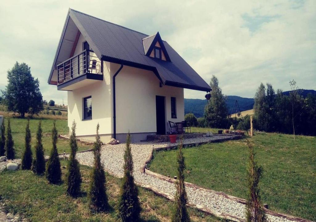 a small white house with a balcony in a field at Domek na Przylasku in Grywałd