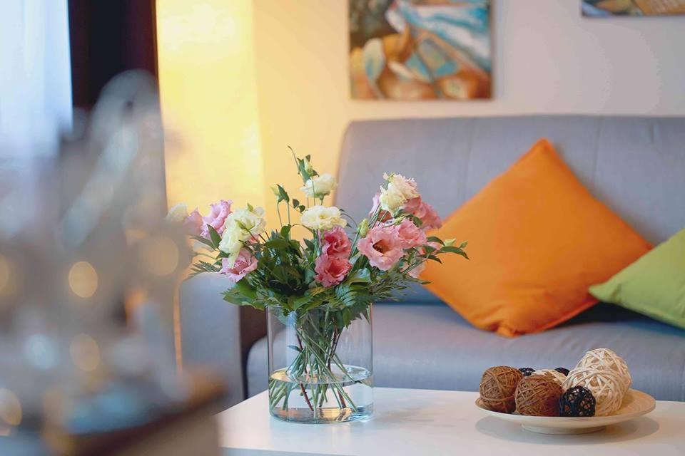 eine Vase mit Blumen auf einem Tisch mit Keksen in der Unterkunft Monarchia Apartman Sunny in Mosonmagyaróvár