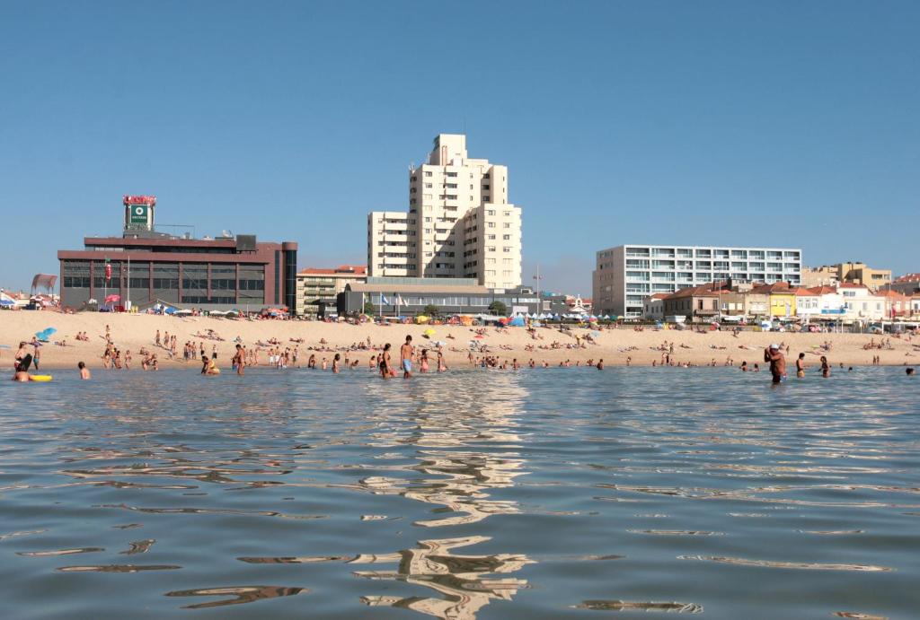 a group of people on a beach in the water at Hotel Apartamento Solverde in Espinho