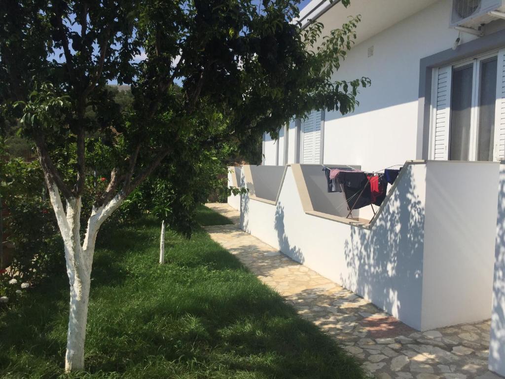 una casa con un árbol junto a una pared en Xuxi Apartments, en Lukovë
