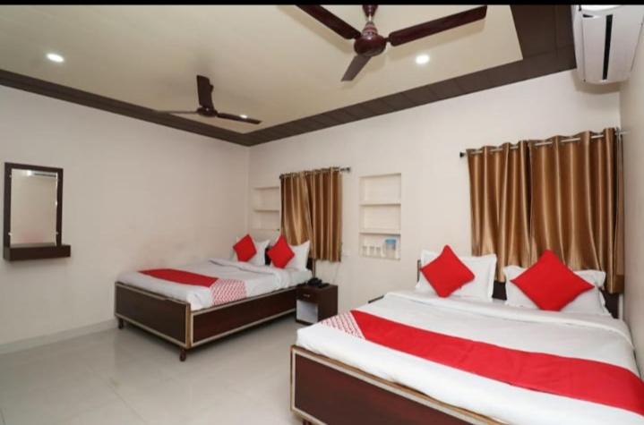 a bedroom with two beds with red pillows at Hotel R D Palace in Varanasi
