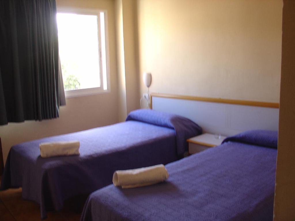 a hotel room with two beds and a window at Pensión Mova in Santa Cruz de Tenerife