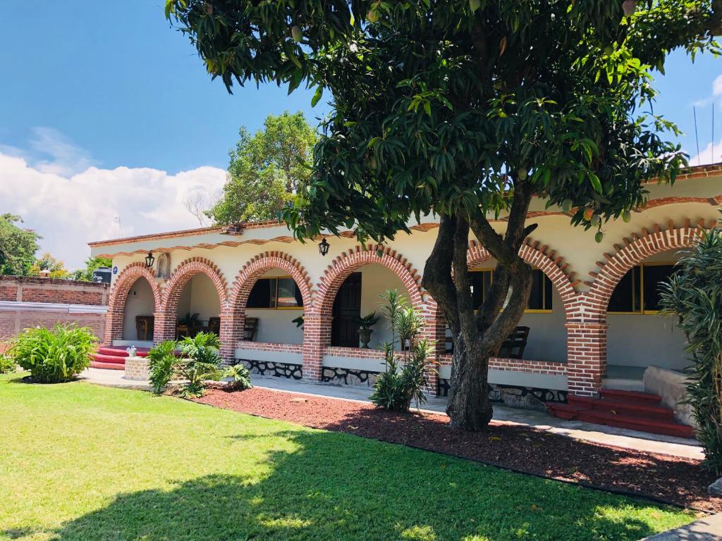 un bâtiment avec un arbre en face d'une cour dans l'établissement Finca Ybarra, casa de campo, à Chapala