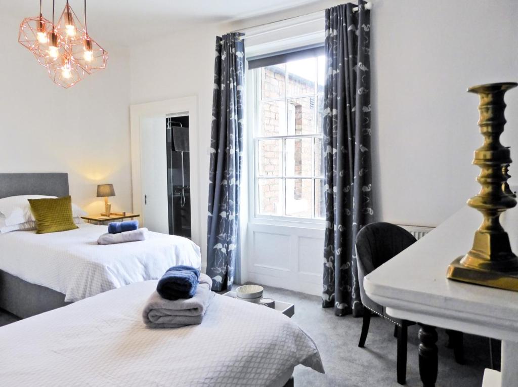 a bedroom with two beds and a desk and a window at Rosalind House in Carlisle