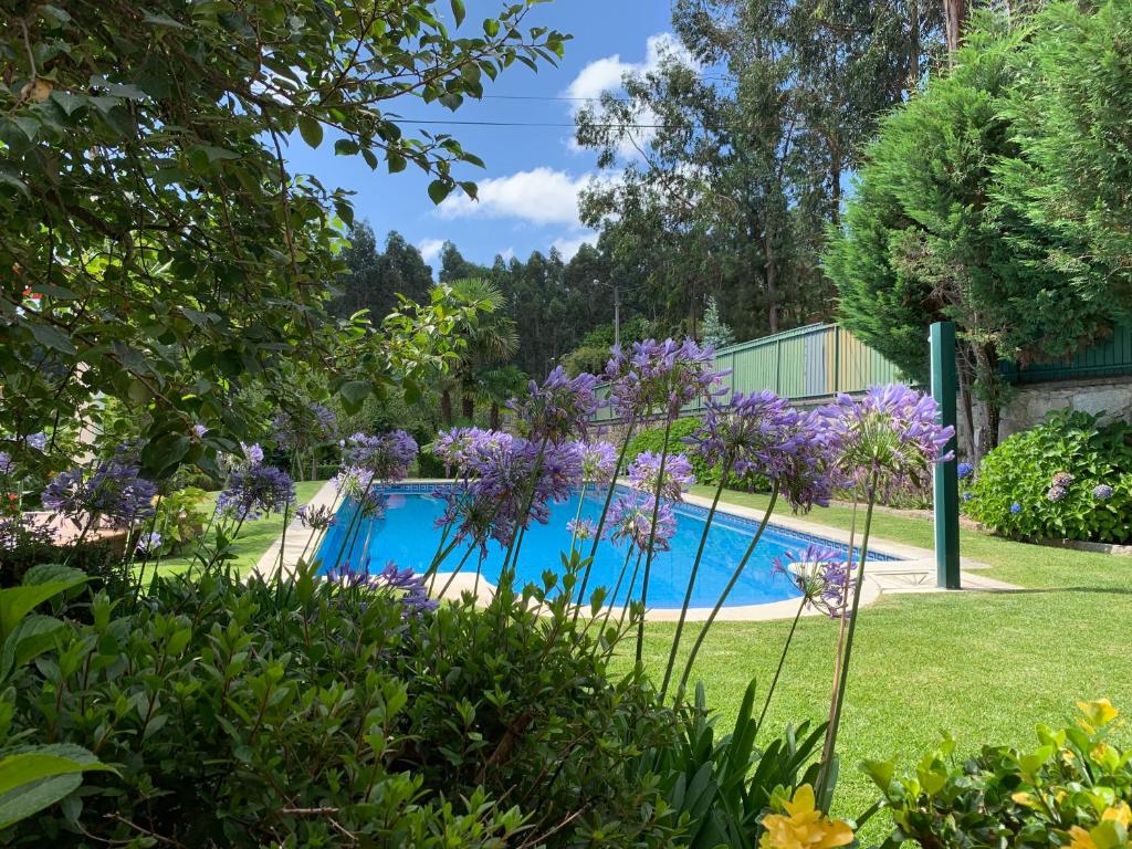 una piscina en un jardín con flores púrpuras en Vila Aurora, en Parada de Gatim
