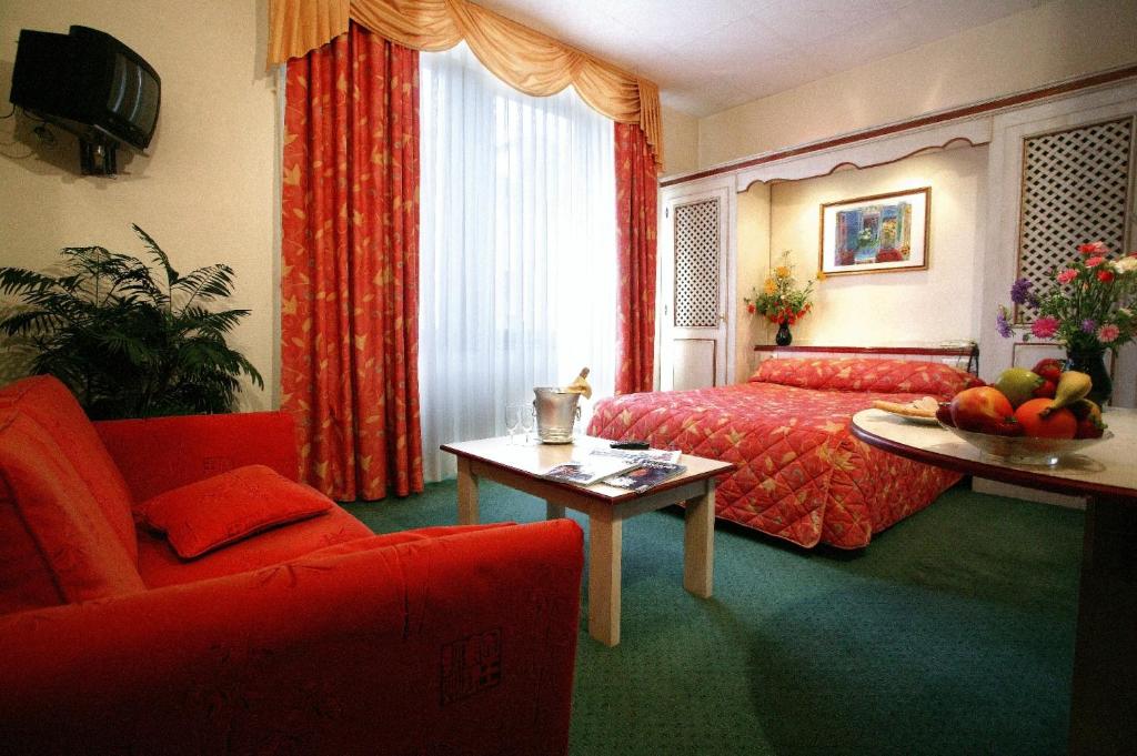 サルグミーヌにあるHotel Unionのベッド、テーブル、ソファが備わるホテルルームです。