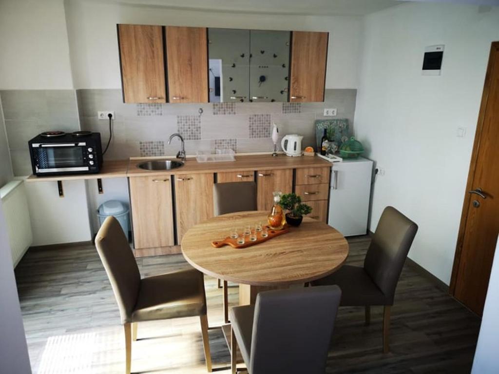 een keuken met een houten tafel met stoelen en een wastafel bij Apartman Borna in Otočac