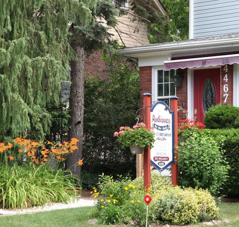 a sign in front of a house with flowers at Ambiance By The Falls B&B in Niagara Falls