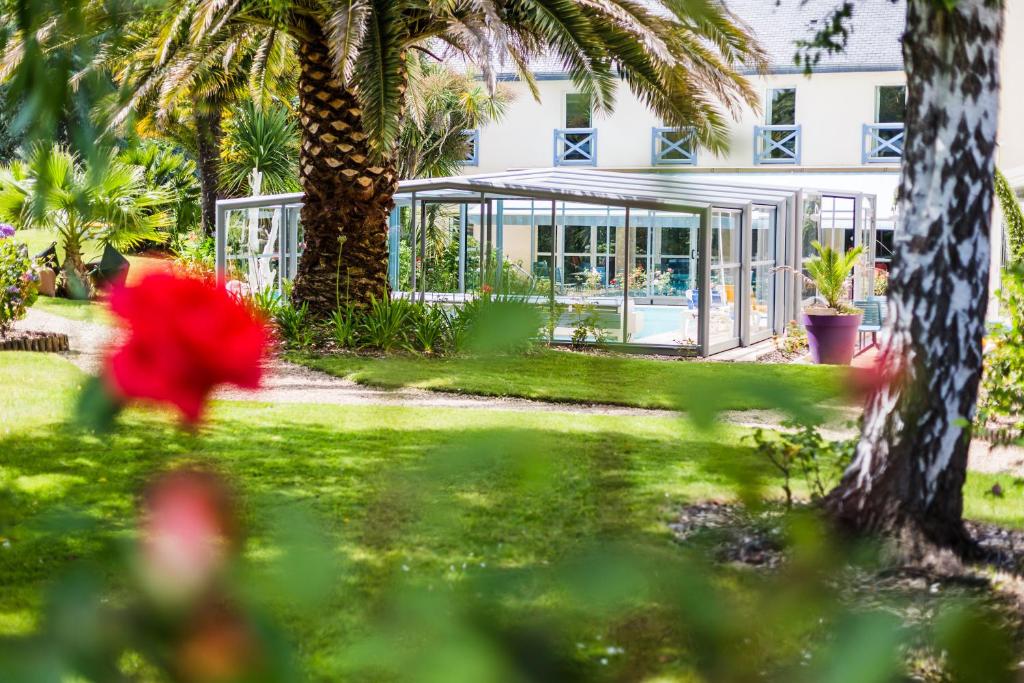 a house with a garden and palm trees in front of it at Hotel Aigue Marine in Tréguier