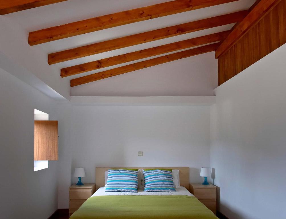 um quarto com uma cama verde e 2 almofadas azuis em Casa De Janeiro em Janeiro de Cima