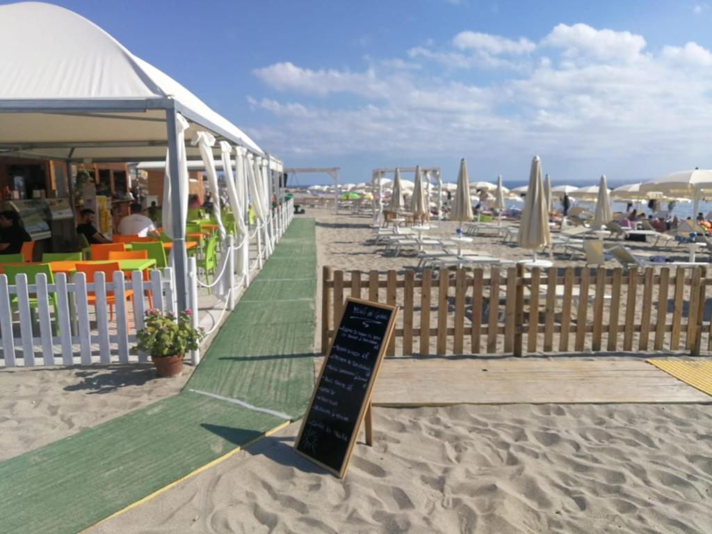 un cartello sulla spiaggia con sedie e ombrelloni di B&B Crispino a Belvedere Marittimo