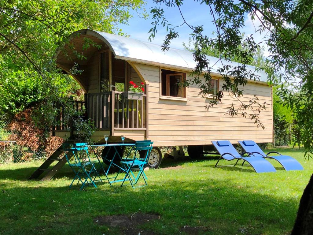 une petite maison avec des chaises et une table dans la cour dans l'établissement Millygite Chalet-on-wheels by the river, à Milly-la-Forêt