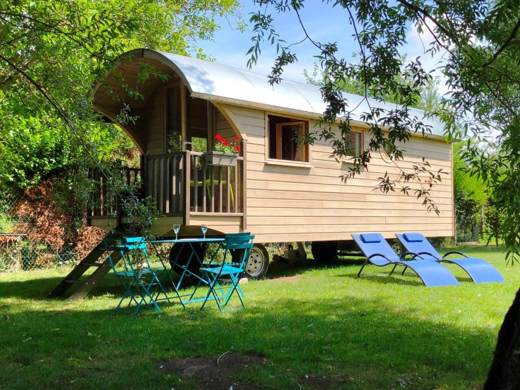 a tiny house with chairs and a table in the yard at Millygite Chalet-on-wheels by the river in Milly-la-Forêt