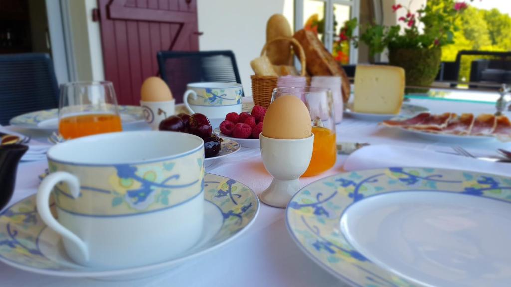 a table with plates and cups and eggs on it at Maison d hotes Lapitxuri in Arcangues