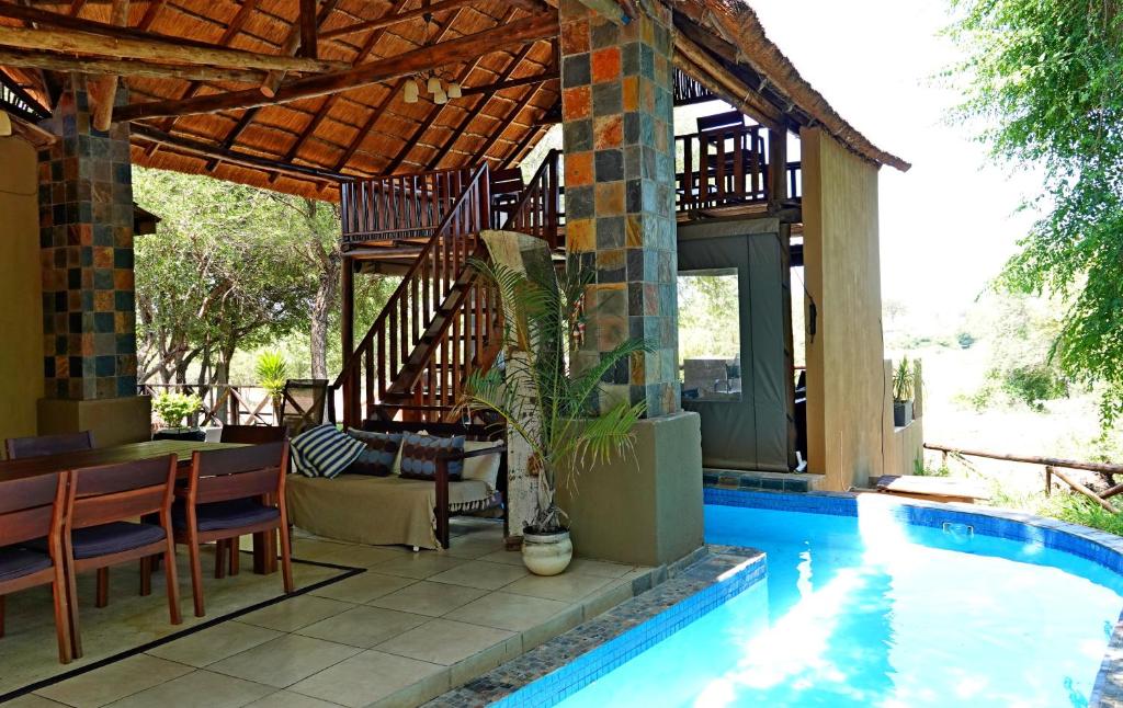une maison avec une piscine à côté d'une maison dans l'établissement Kruger River Holiday Home, à Marloth Park