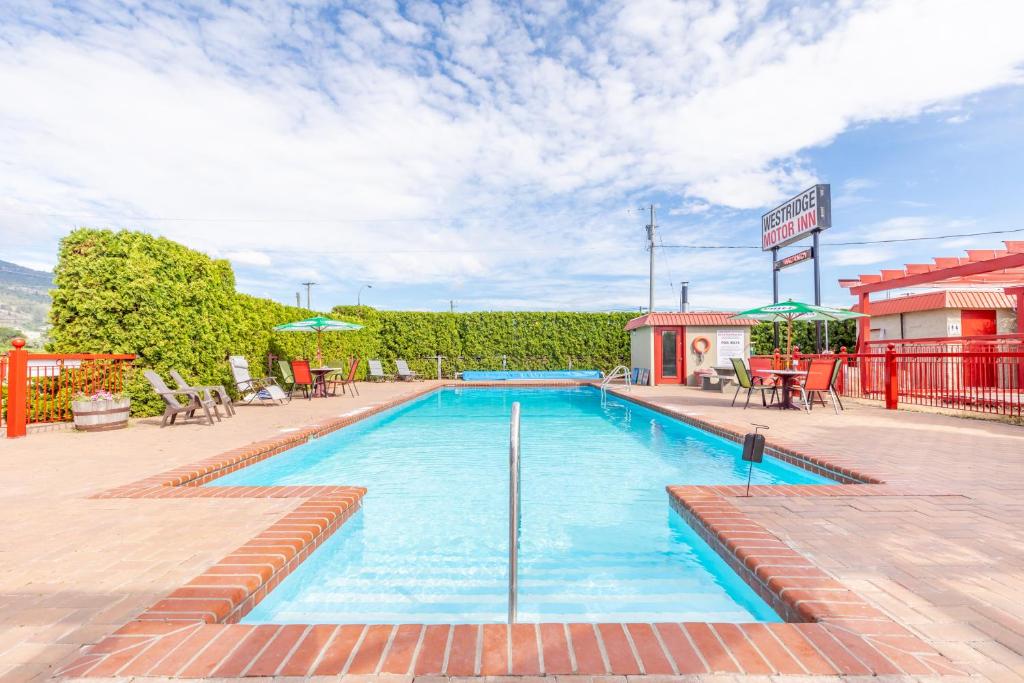 a swimming pool in a resort with chairs and tables at Westridge Motor Inn in Osoyoos