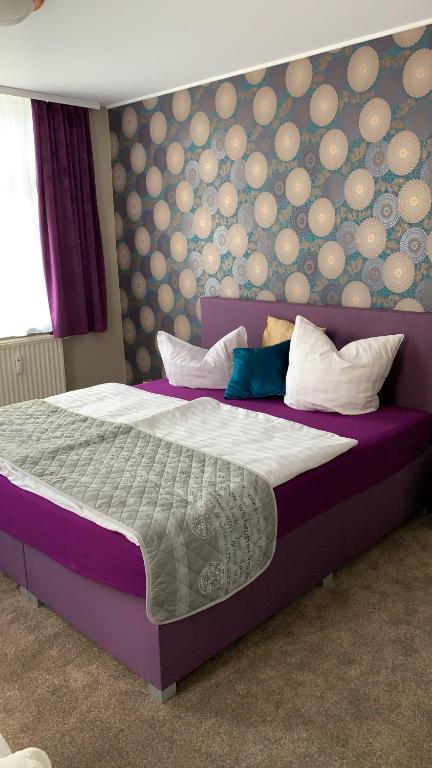 a bedroom with a large bed with a purple headboard at Pension Triebischtal in Meißen