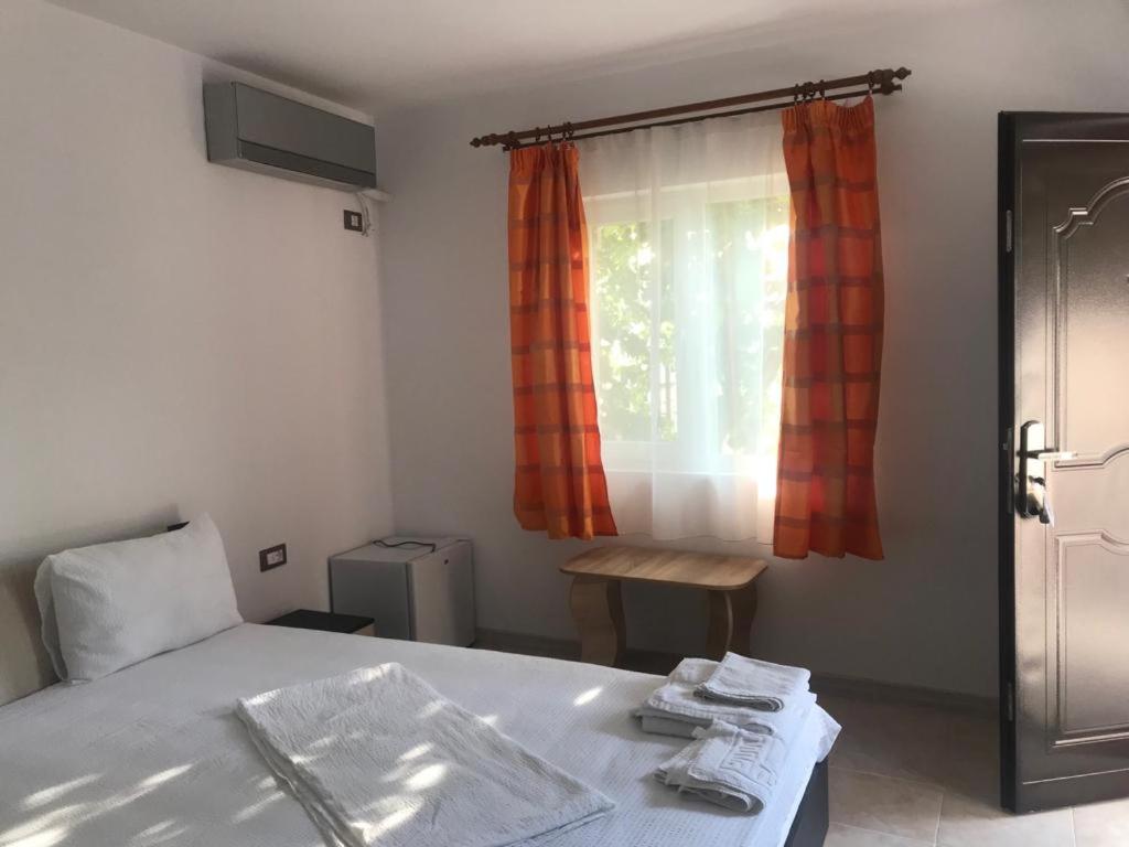 a bedroom with a bed and a window with orange curtains at Raven Comstar in Corbu