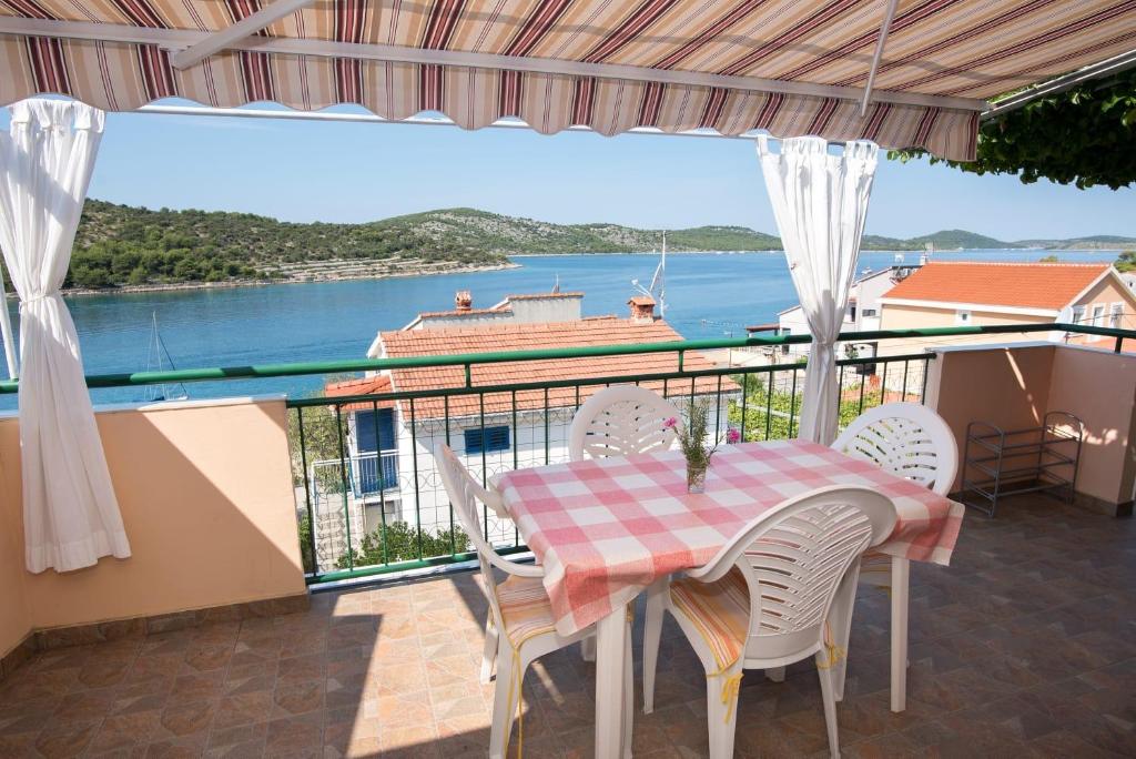 una mesa y sillas en un balcón con vistas al agua en Apartments Vjera en Kaprije