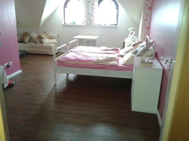 ein Schlafzimmer mit einem rosa Bett und einem Sofa in der Unterkunft Boarding-Haus, Ostercappeln in Ostercappeln