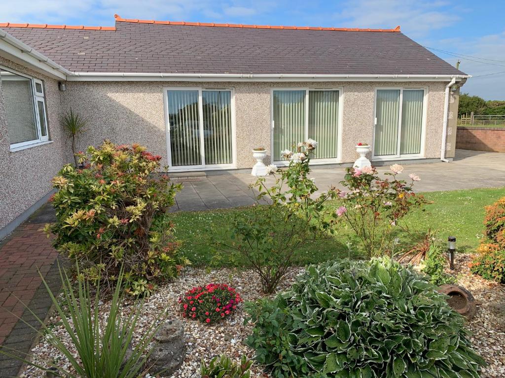 a home with a garden with flowers and plants at Coed Bach Suite in Bryngwran