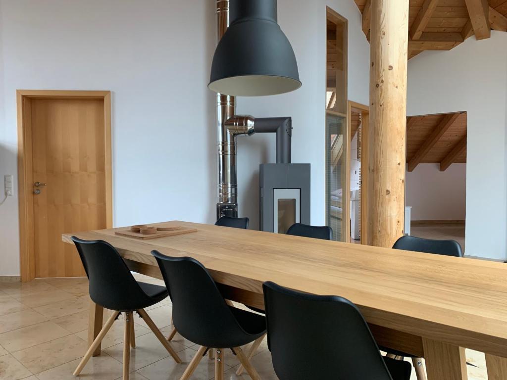 uma grande mesa de madeira com cadeiras e uma luz negra em City Dachterassenwohnung em Rosenheim