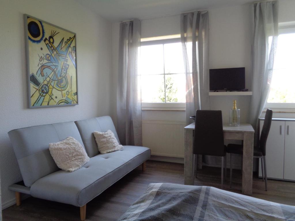 a living room with a couch and a table and window at Studiozimmer an den Leineauen in Arnum