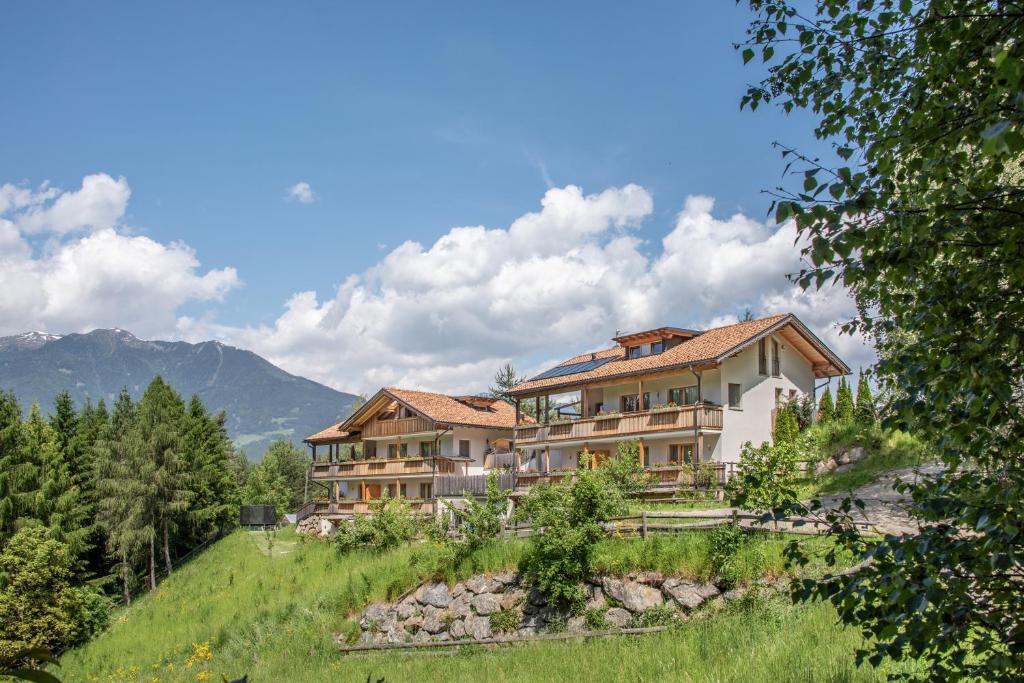 uma casa grande numa colina com montanhas ao fundo em Apartmenthaus Fuchsmaurer em Bressanone