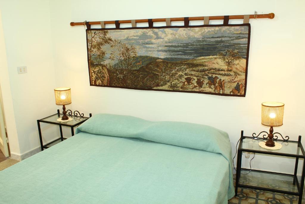 een slaapkamer met een bed met een schilderij aan de muur bij Borgo del Barone in Carini