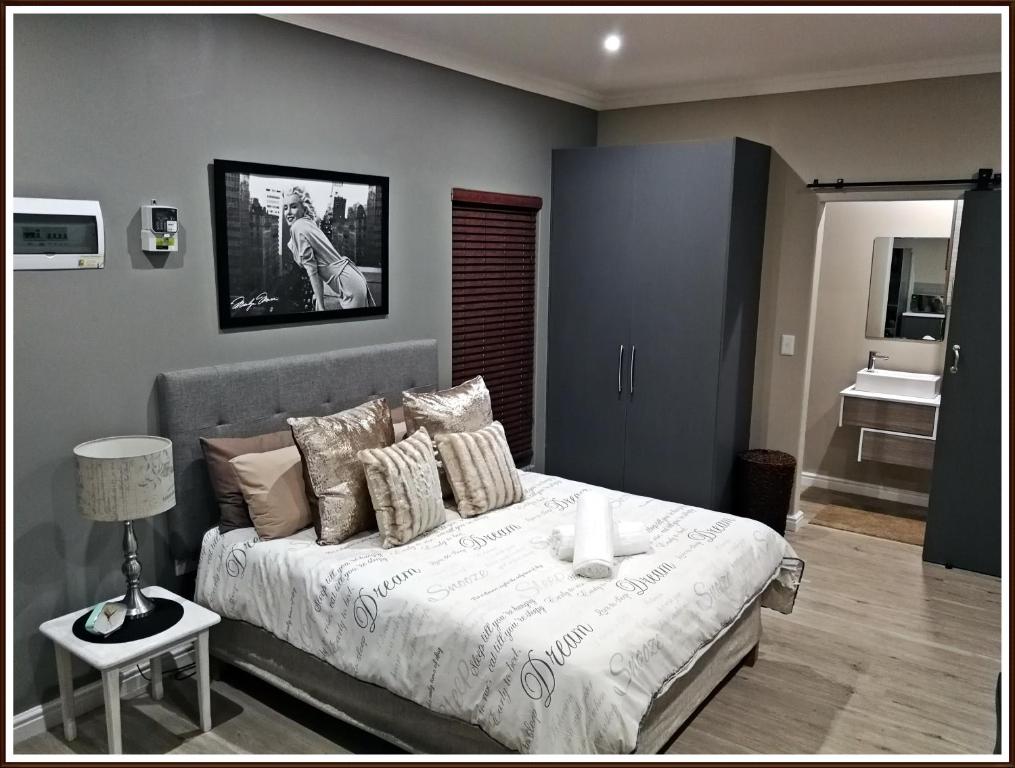1 dormitorio con 1 cama con mesa y lámpara en Studio 77 en Langebaan