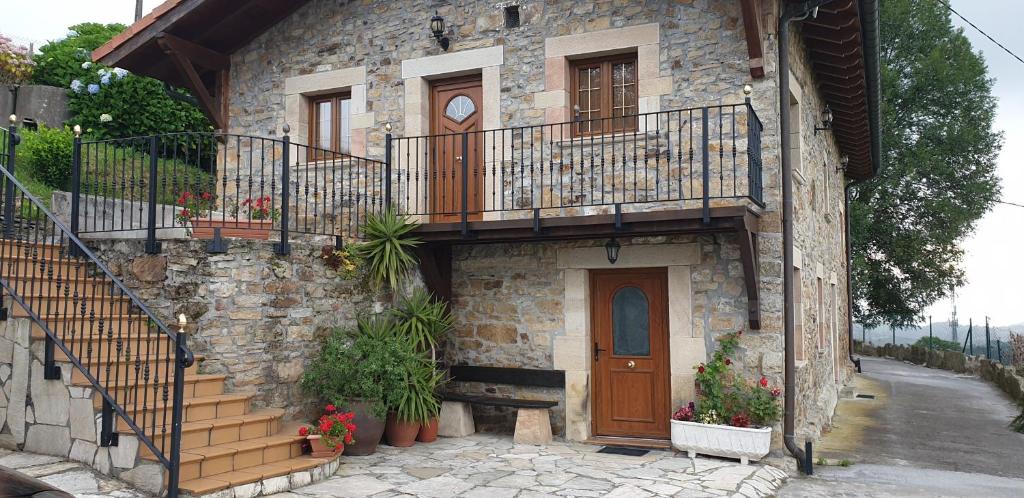 a stone house with a staircase and a wooden door at La Casa del Acebal in Solórzano