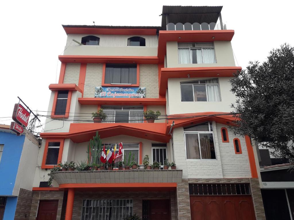un edificio alto con banderas delante en Hostal Turístico El Cajamarquez, en Lima